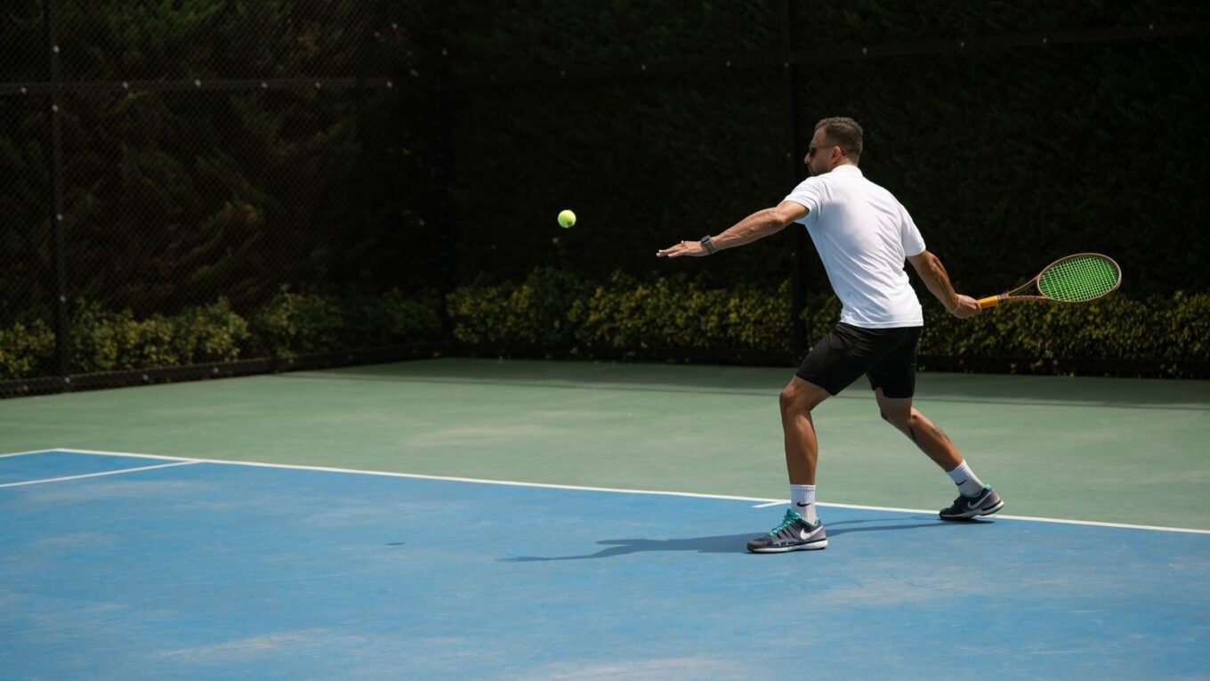 Tennisspelare slår en boll på en utomhusbana