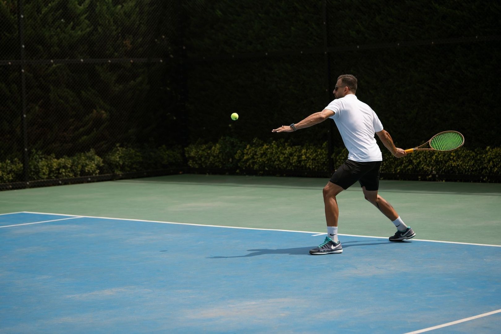 Tennisspelare slår en boll på en utomhusbana