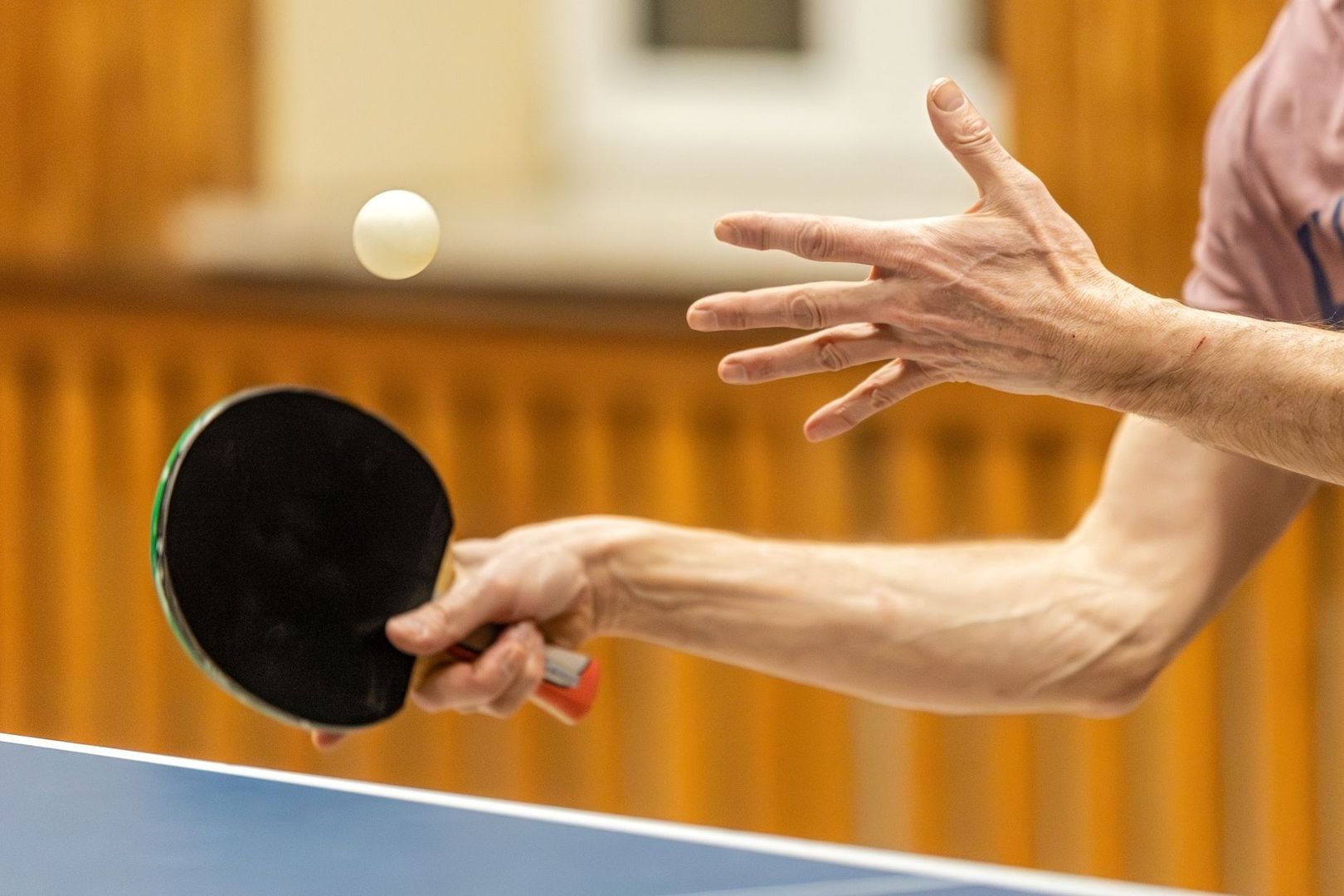 Närbild av bordtennisspelare som slår en boll med racket
